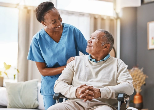 medical assistant speaking with senior patient while pushing him in wheelchair